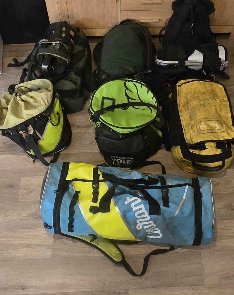 Seven climbing kit bags lined up on the floor, booked in for inspection