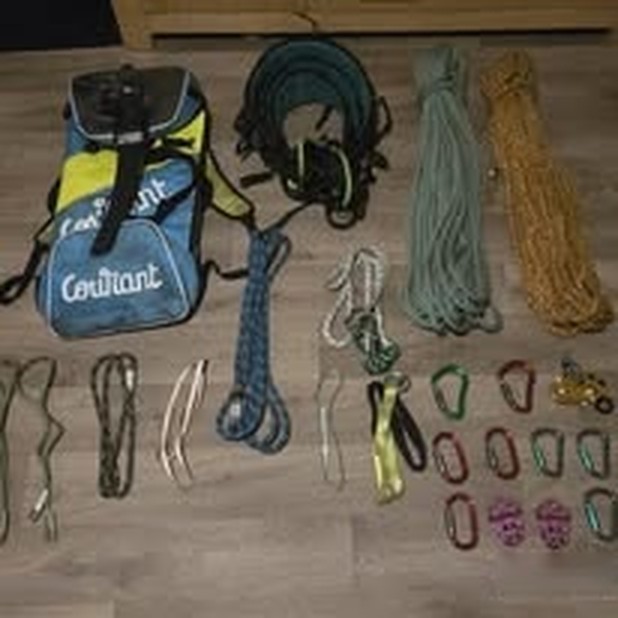 Climbing ropes, lanyards, slings and karabiners laid out in rows next to a kit bag